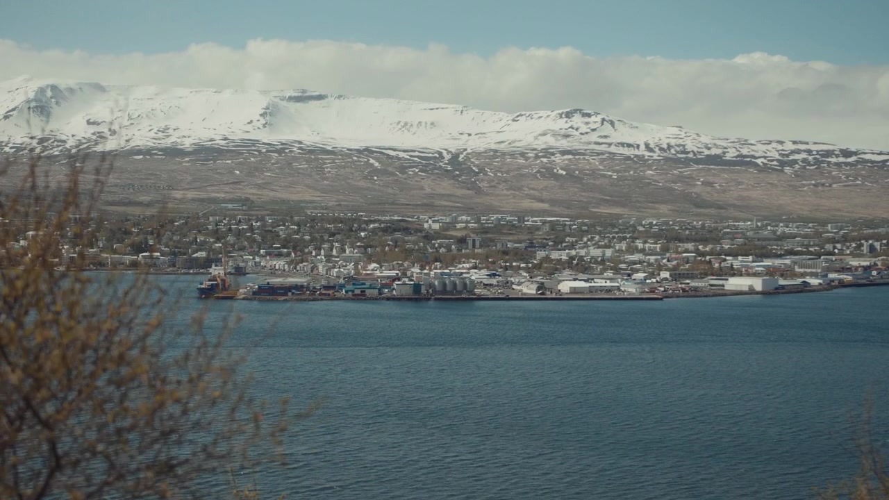 Vista panorámica de un pueblo costero con montañas cubiertas de nieve
