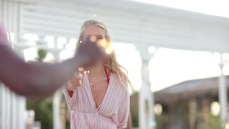 Happy-diverse-group-of-friends-dancing-with-sparklers-at-beach