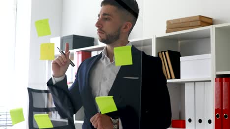 businessman making notes in stickers on glass wall