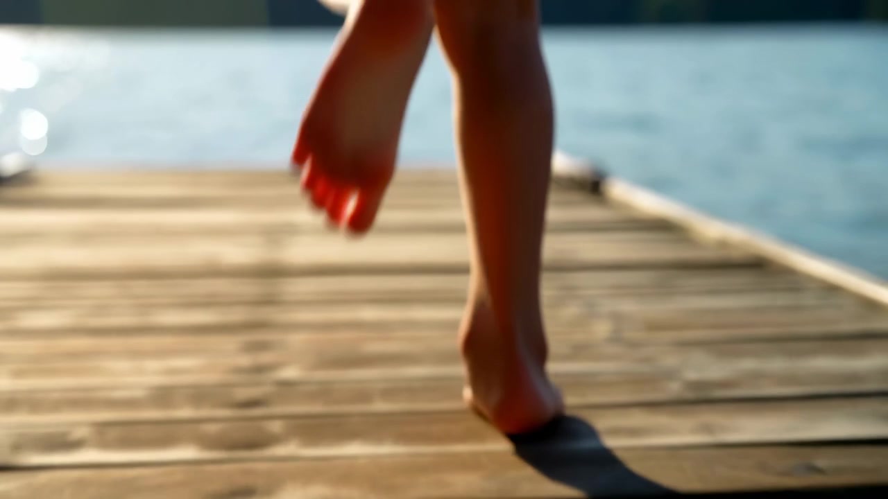 Primo piano dal basso delle gambe e dei piedi nudi di un bambino che si muovono su assi di legno stagionate accanto ad acqua calma, con luce diurna calda, sfocatura dello sfondo soffusa e un