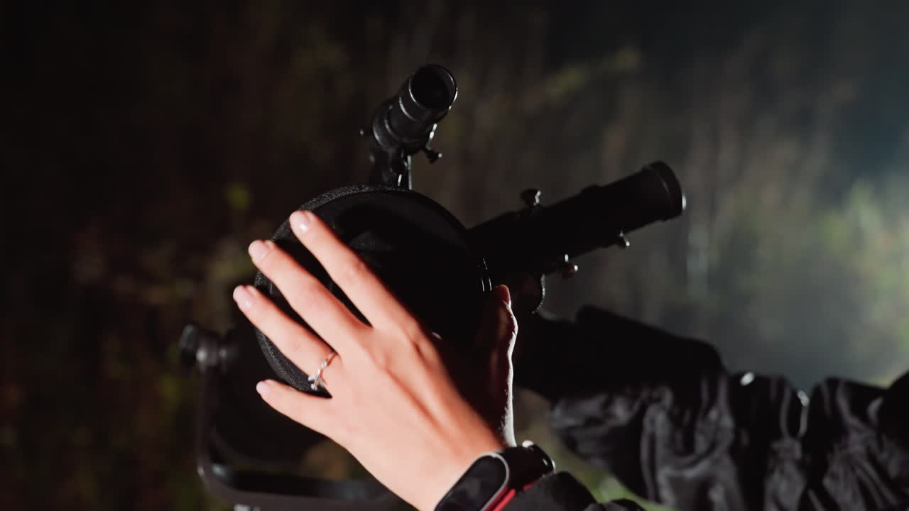 mani che calibrano rapidamente il telescopio notturno, il tecnico sul campo esegue un allineamento rapido per la mappatura del cielo profondo, mirino e treppiede visibili, rugiada sul tubo, smartwatch che monitora l'ora, ritmo sostenuto