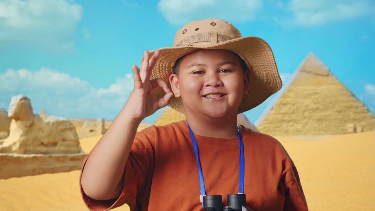 Asian Boy With A Hat Showing Okay Gesture After Looking Through The Binoculars. Boy Researcher Examines Something While Traveling In Giza Pyramid, Travel Tourism Adventure Concept, Close Up