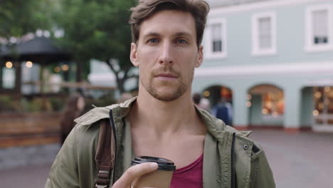 portrait of handsome young man looking pensive thoughtful at camera holding coffee beverage urban background