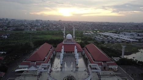 reveal drone shot of the great mosque of central java (majt) in suset time. th sun is orange and the weather is cloudy