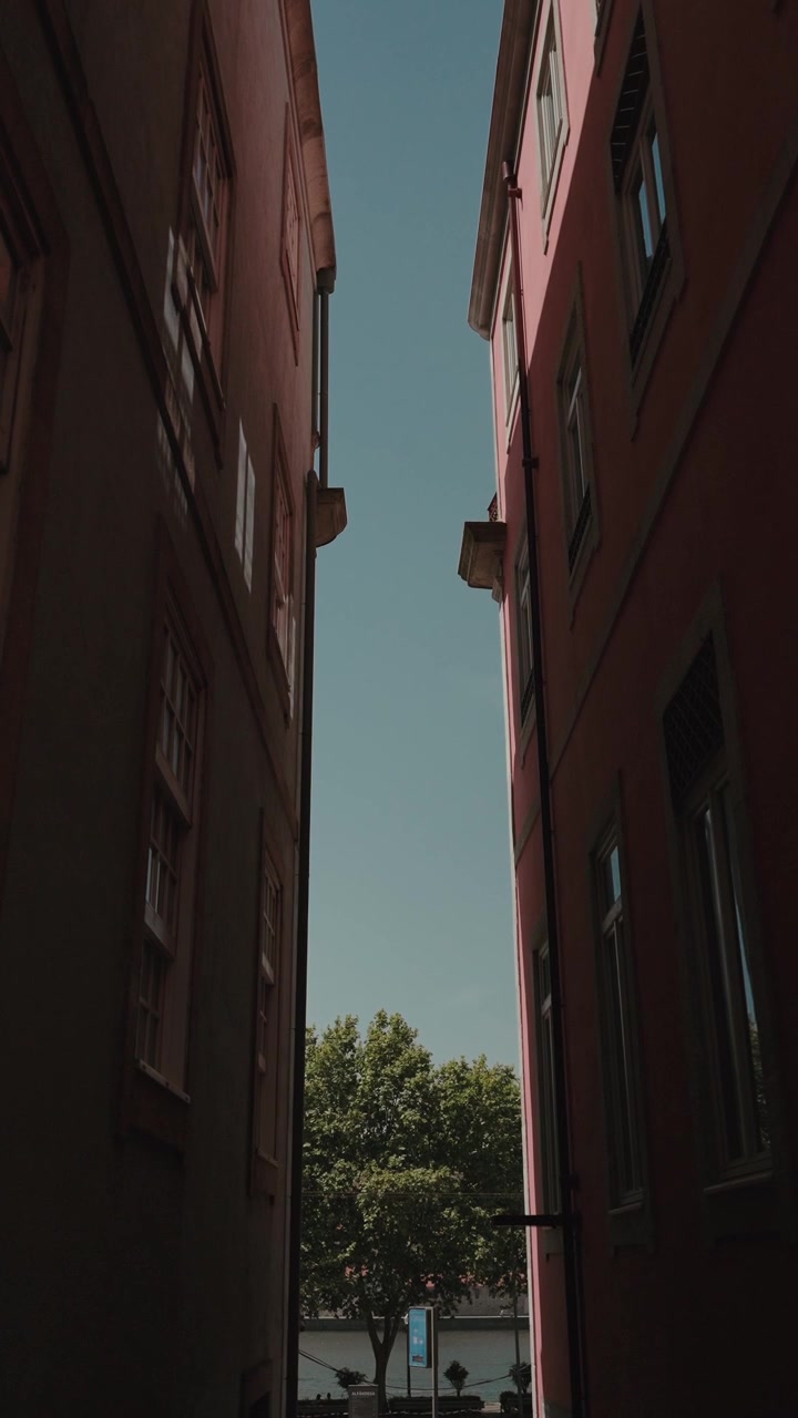 Spazio ristretto tra edifici urbani con il cielo visibile sopra e un albero alla fine