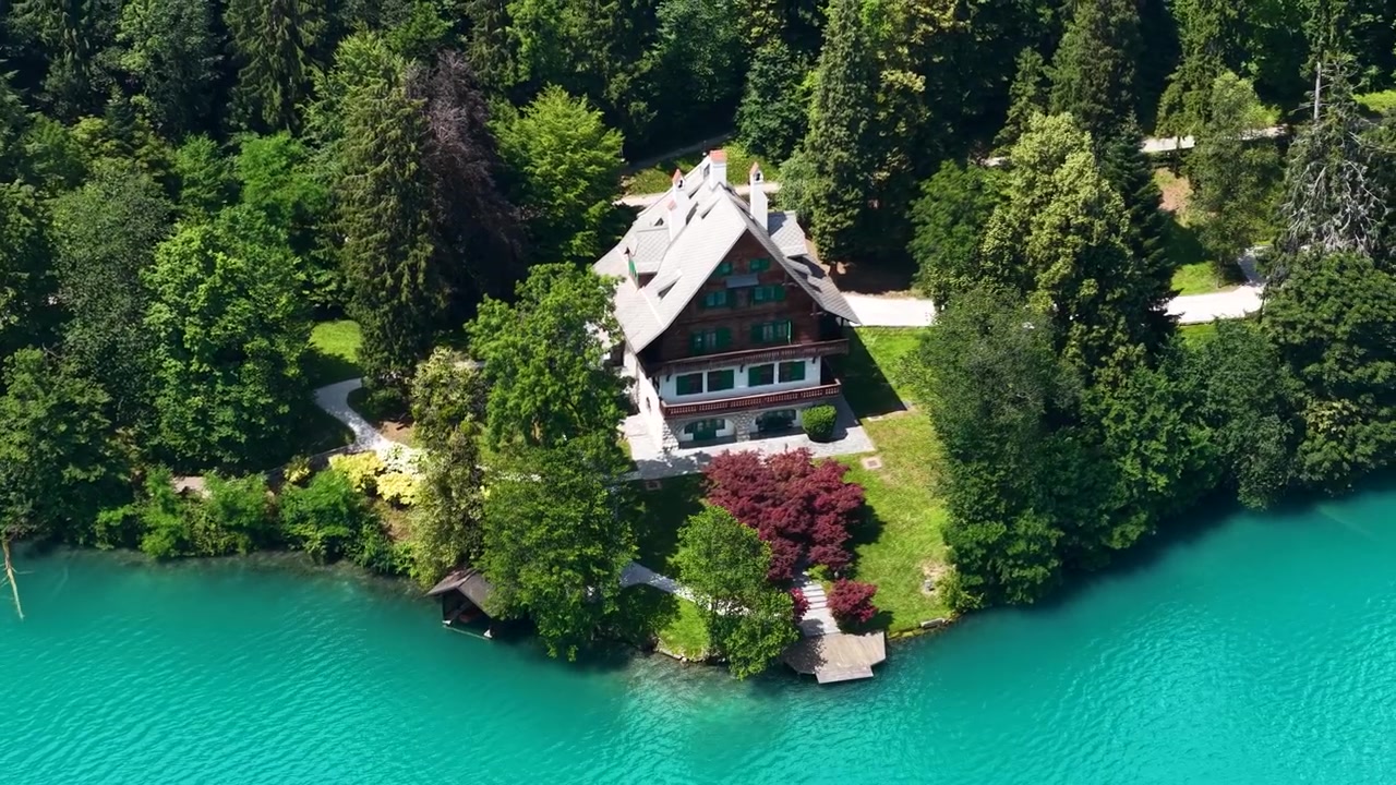 Ripresa con drone di una villa sul lago di Bled, Slovenia. Casa con giardino e molo in una foresta verde