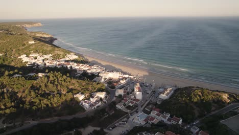Aerial-over-the-city-of-Salema,-its-beach-and-various-hotel-resorts