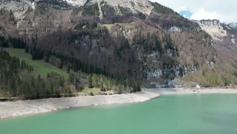 aerial forward view of shoreline of an alpine lake in a fantastic mountain landscape