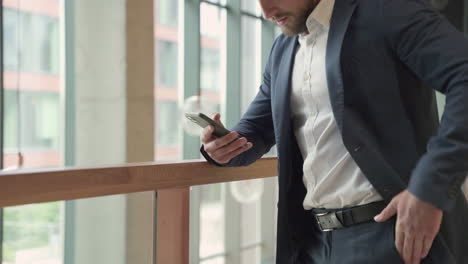 An-Attractive-Young,-Bearded-Businessman-In-A-Blue-Blazer-Consults-His-Smart-Phone-Attentively-1