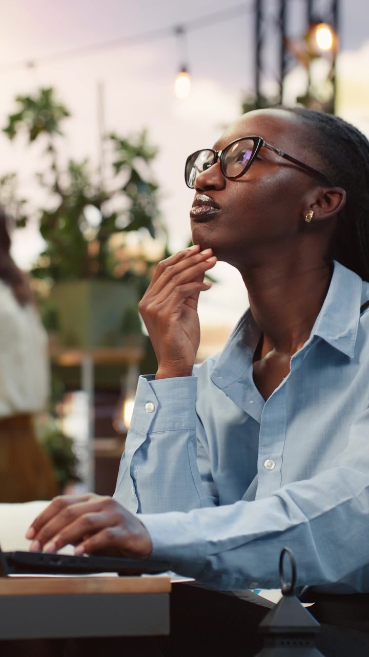 Vertical video Businesswoman works on laptop from rooftop lounge, doing brainstorming