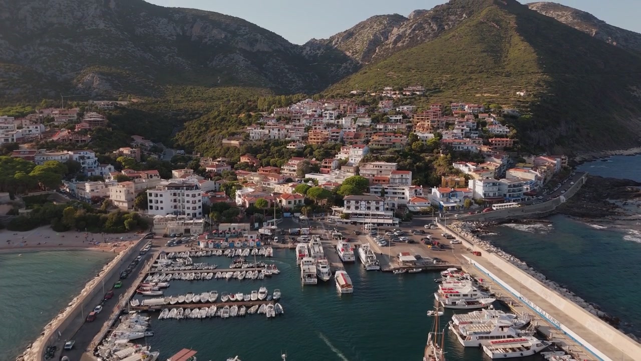 Coste mediterranee, destinazioni turistiche, porto pittoresco, Porto di Cala Gonone, Sardegna, Italia, Europa, ripresa aerea con movimento di inclinazione e carrello.