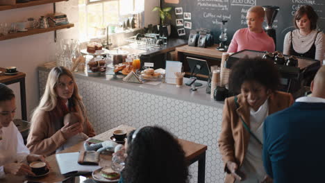 Gente-Diversa-En-La-Cafetería-Barista-Mujer-Sirviendo-A-Los-Clientes-Comprando-Café-En-Un-Restaurante-Concurrido