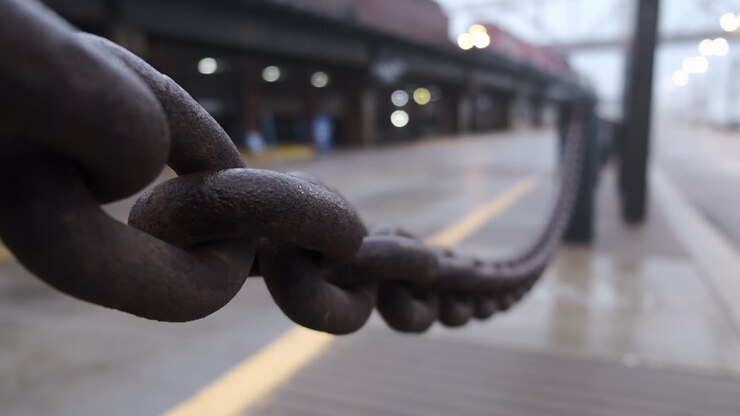 Close up an iron chain with a defocused monorail traveling in the background