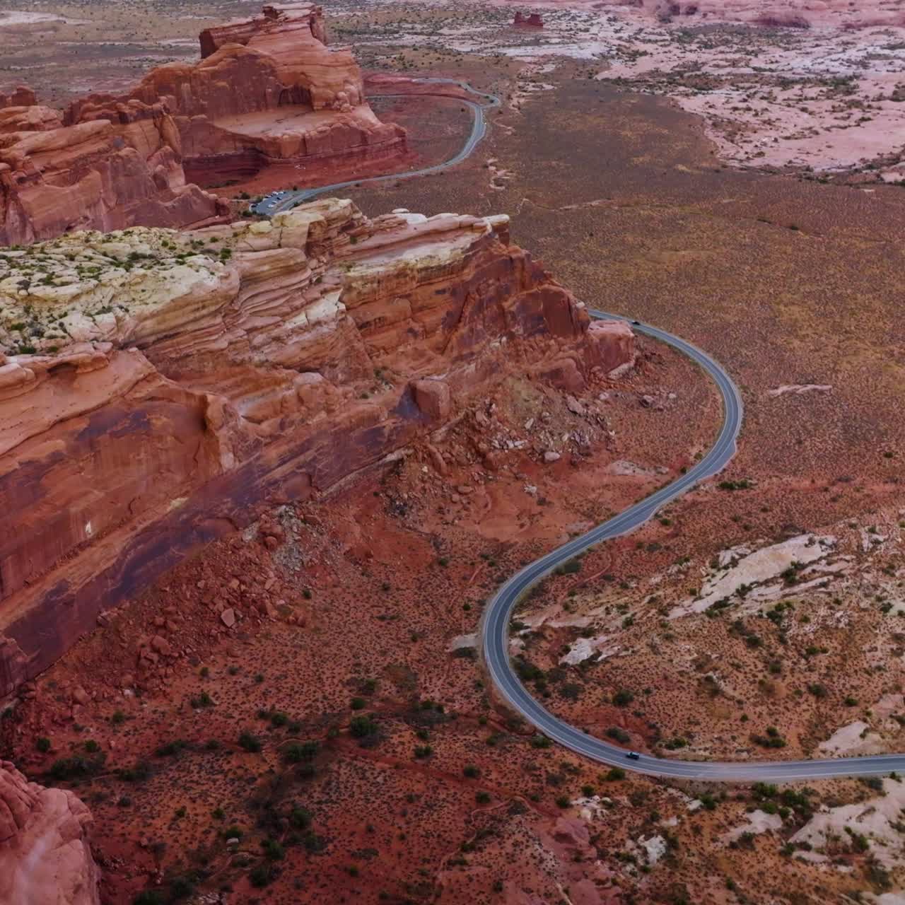 Curvy road going round the majestic rocks of Utah National park. Amazing canyons and deserted lands from aerial perspective