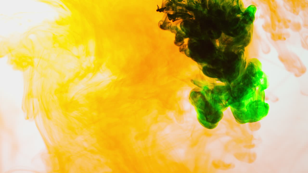 зелёная и оранжевая краска или краситель падают в воду на белом фоне, чтобы создать вихревый цветный дымовый фон 2