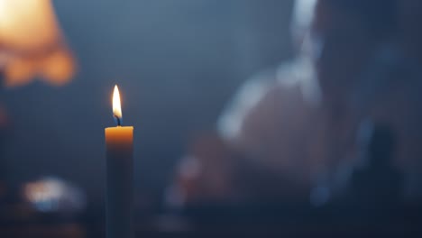 hombre trabajando en bokeh en un escritorio en la oscuridad iluminado con una vela