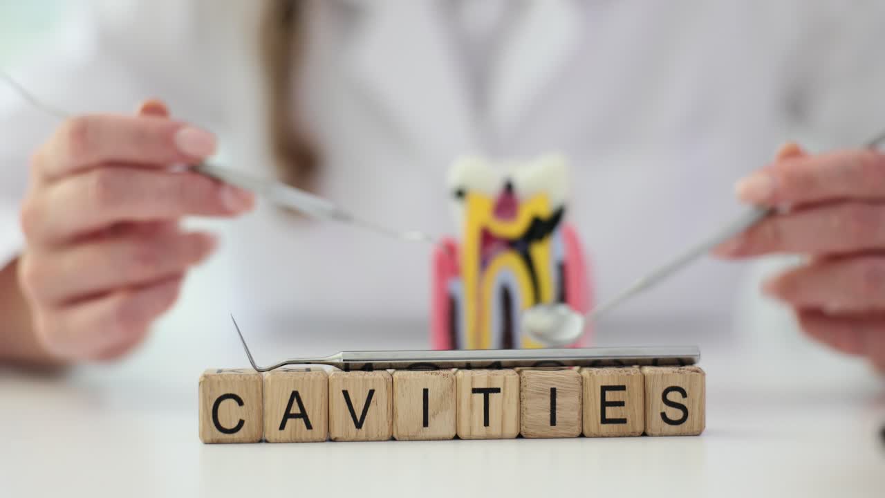 Close-up of 'Cavities' spelled on wooden blocks with dental instruments and a tooth model