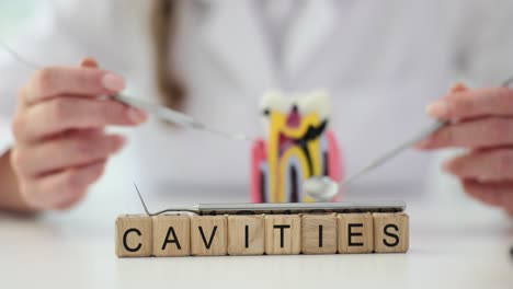 close-up of 'cavities' spelled on wooden blocks with dental instruments and a tooth model