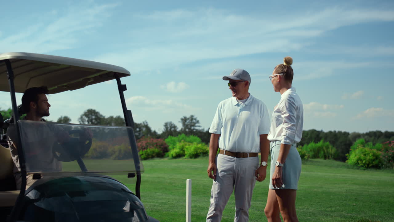 Golf players group chatting together at fairway. Golfers driving cart outdoors.