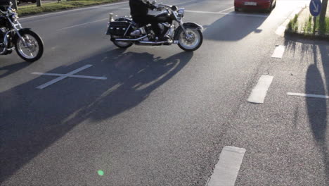 Silhouettes-of-heavy-motorbikes-crossing-a-big-street-at-sunset,-frontlighting