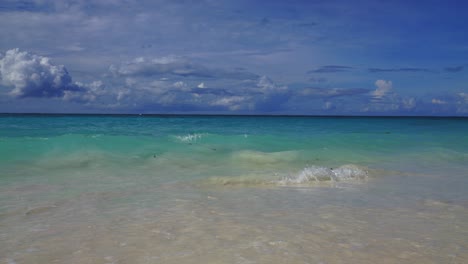 a slow motion sequence of a tropical beach with small waves gently crashing against the shore