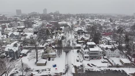 triple-deckers line a quiet road in worcester, massachusetts. downtown towers rise over neighborhood rooftops. sweeping above city blocks, aerial.