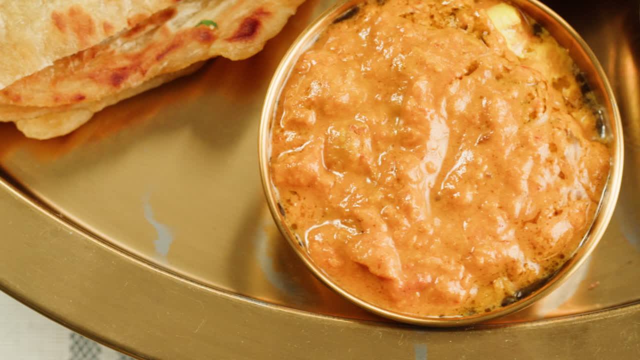 Assorted indian sri-lanka food set on wooden background. Dishes and appetisers of indeed cuisine, rice, lentils, paneer, samosa, spices, masala. Bowls and plates with indian food top view chicken. High quality 4k footage