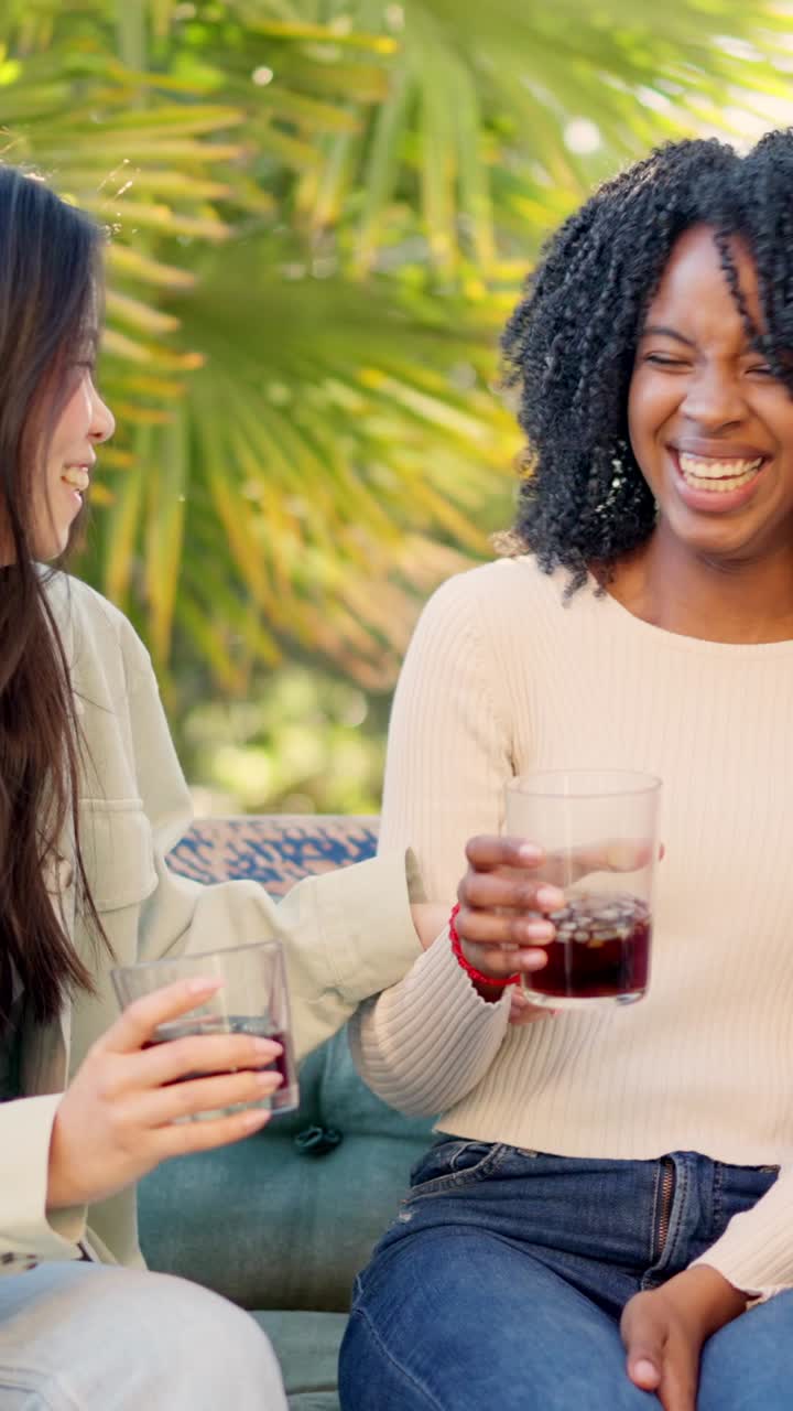 Multi-ethnic friends smiling and drinking in the garden