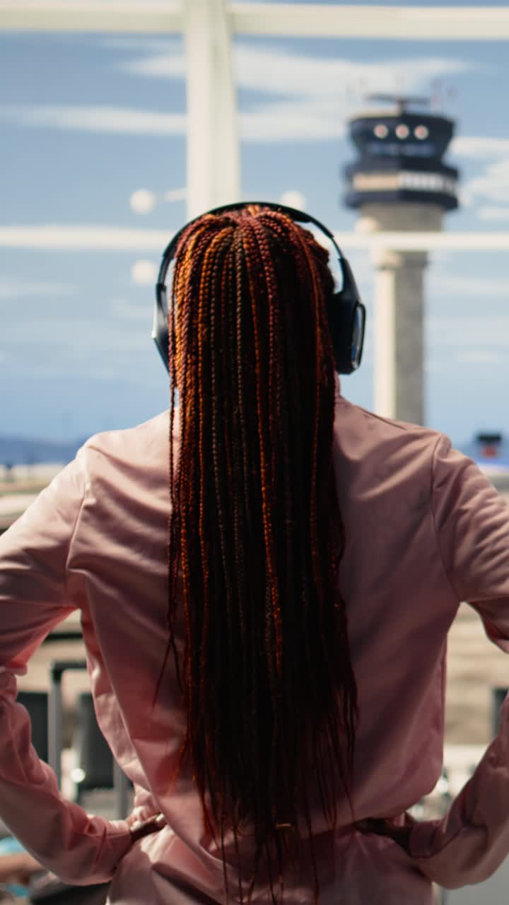 Video verticale: ragazza afroamericana che ascolta musica e aspetta l'imbarco sull'aereo.
