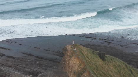 Aerial-drone-shot-of-a-man-over-a-cliff