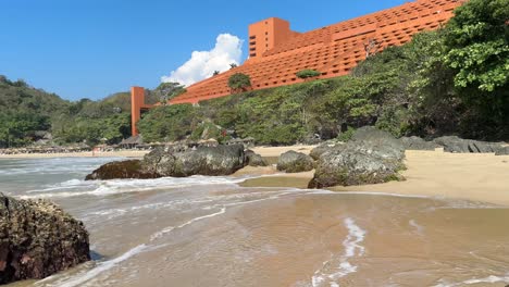 Surf-washing-on-sunny-sandy-beach-in-front-of-tropical-resort