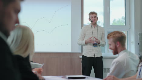 man-speaker-is-reporting-showing-charts-and-answering-on-questions-of-audience-in-business-meeting