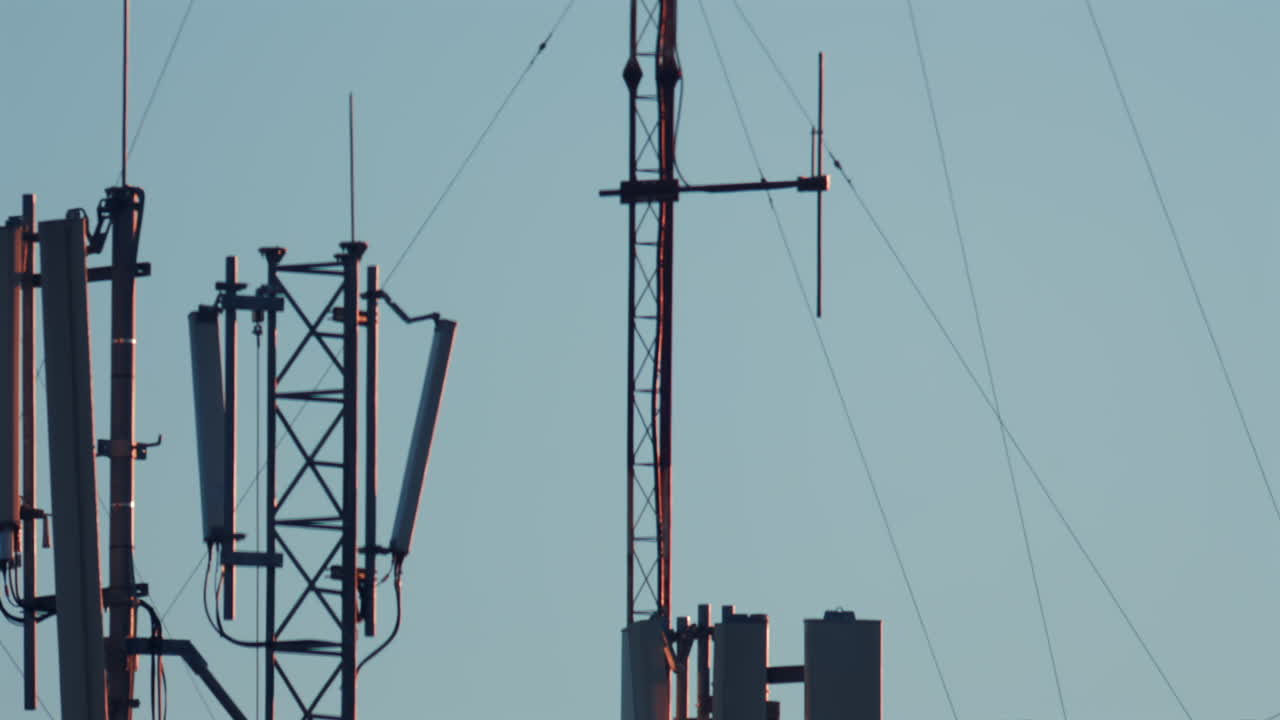 Antennas and communication towers stand on top of a building under the warm morning light