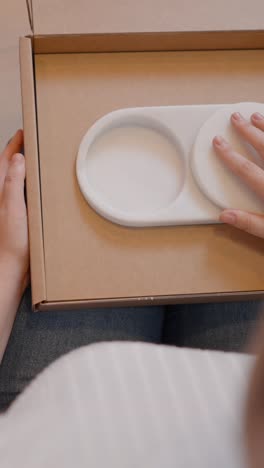 unboxing a white oval tray with circular lids/coasters