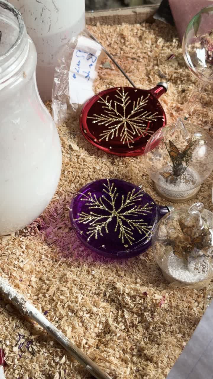Close up of beautiful handmade glass Christmas ornaments with golden glitter snowflakes in craft workshop setting. Perfect for holiday DIY and creative hobby content