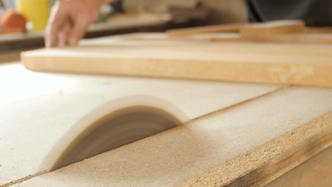 young man cuts a wooden board with a circular saw blade, a workshop with a professional tool for woodworking, a concept of construction working process of manufacturing parts for construction