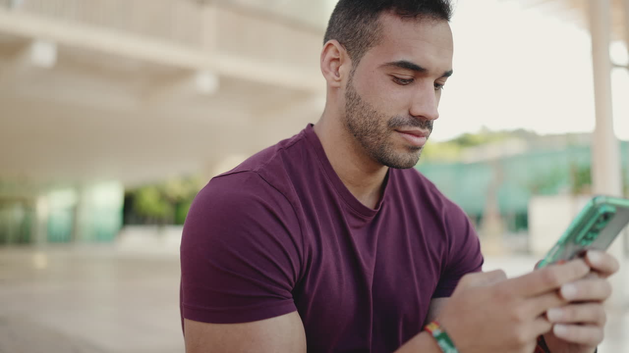 Young man texting on smartphone and sitting outdoors.