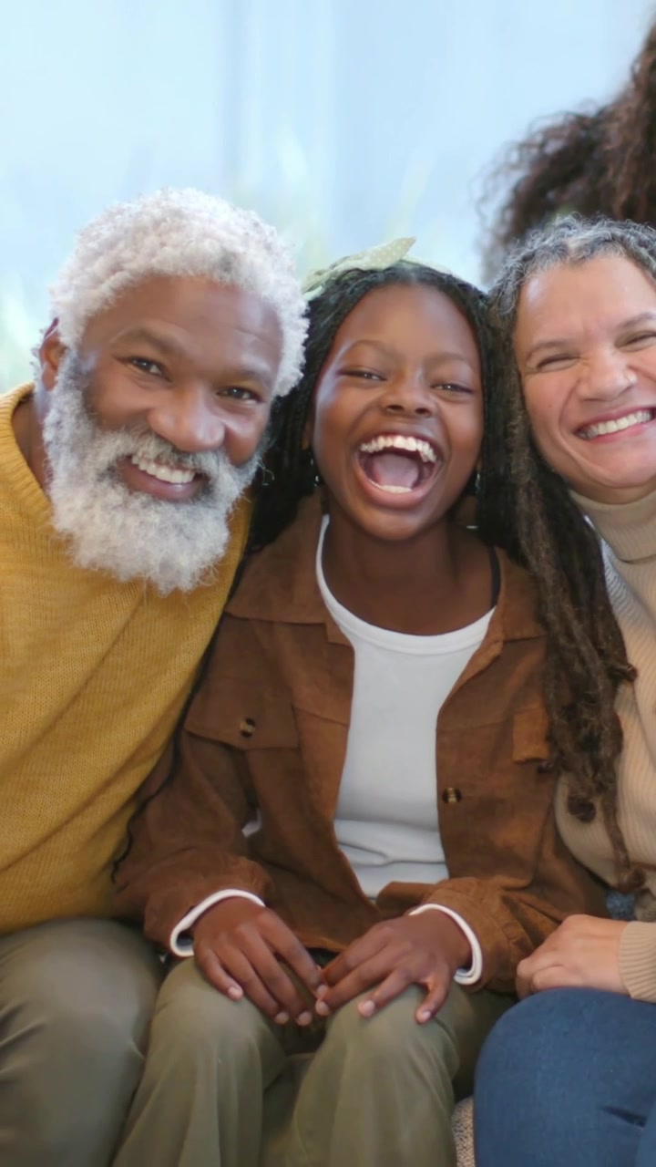 Vertical video: Opening family trio turning heads giggling and leaning on sofa sharing joy