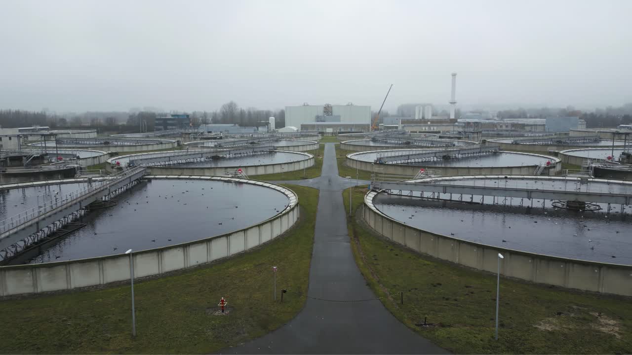 Renewable energy solar installation in foreground with water treatment infrastructure visible in background showing sustainable industrial systems