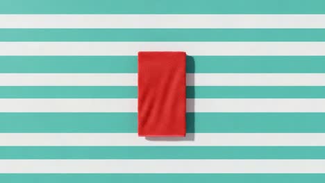 a bright red towel positioned on a bold striped background, showcasing contrast and vibrant colors in a simple yet captivating composition