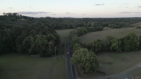 green flat light aerial follows vehicle on suburb estate road in nsw