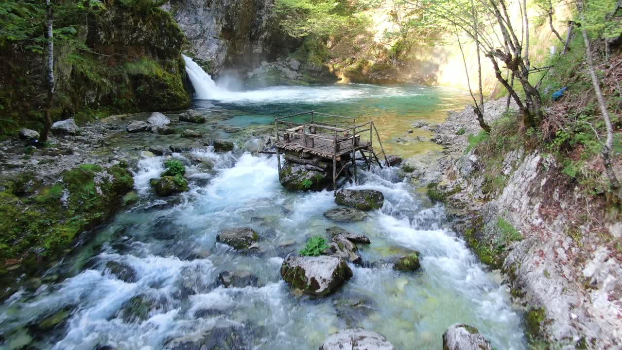Drone view in Albania in the alps flying on top of a rapids river towards a waterfall in Theth