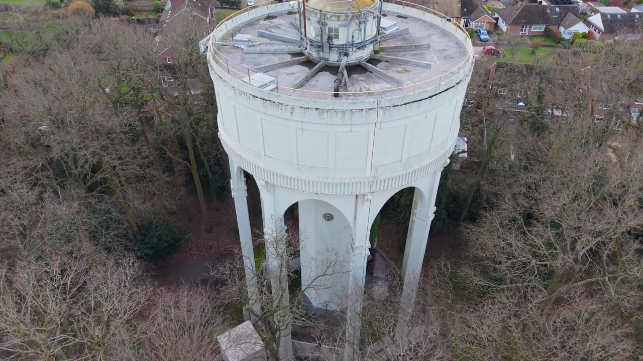 Der Drohnenaufstieg am Wasserturm Bengeo mit feststehender Kameraführung enthüllt zunächst Kommunikationsantennen auf dem Dach, bevor er sich zu den Dächern des Dorfes Hertfordshire, Bäumen und dem ländlichen Horizont weitet.