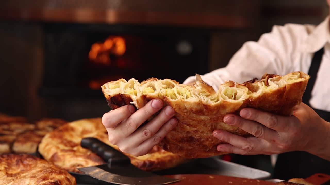 Primo piano di mani che aprono un Burek appena sfornato