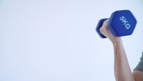brazo levantando una manivela de 5 kg contra un fondo blanco en cámara lenta