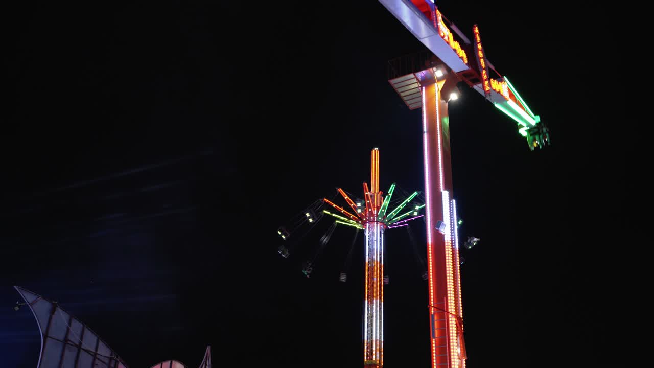4k péndulo intermitente multicolor en el parque de atracciones girando balanceando sus grandes brazos por la noche