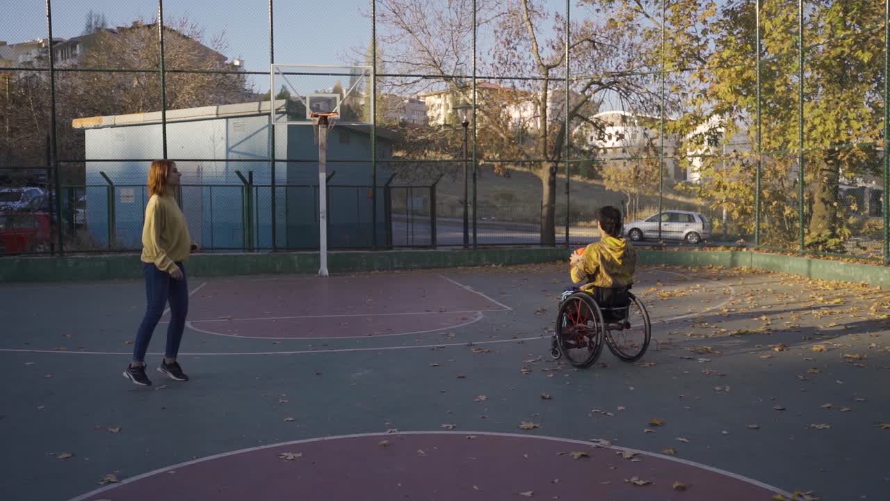 un joven en silla de ruedas y su novia jugando al baloncesto en cámara lenta.