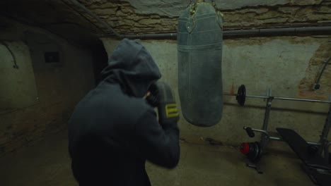 in weathered gym, a boxer in hoodie delivers powerful punches to swaying bag