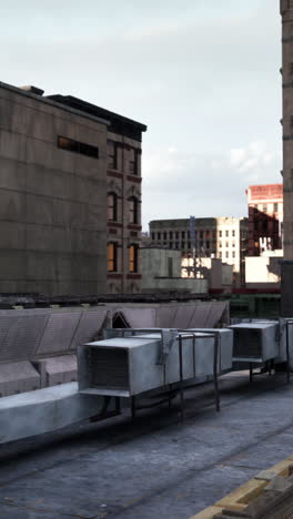 a view of a city rooftop with vents and buildings in the background