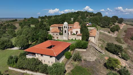a stunning bird's-eye view of the ancient church and ruins in apollonia, albania, illuminated by warm sunshine. the scene captures the historical charm of the site, blending nature and heritage.